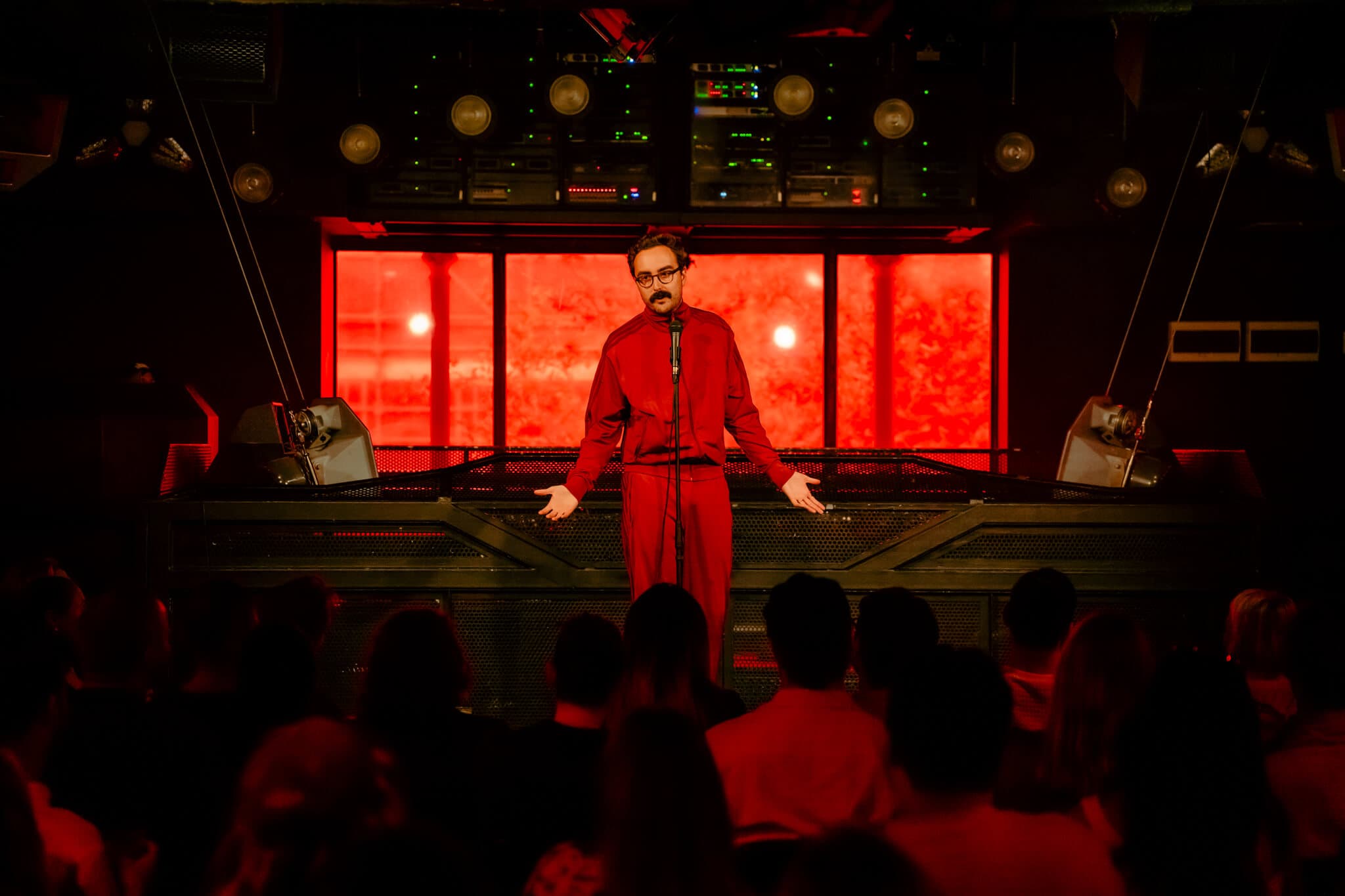 A comedian on the Carousel stage under red light