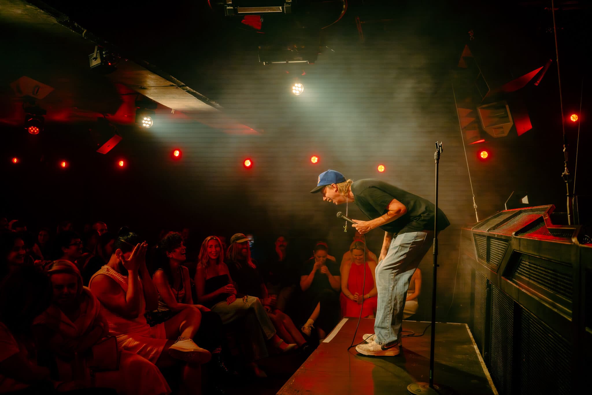 A comedian leaning into the front tables