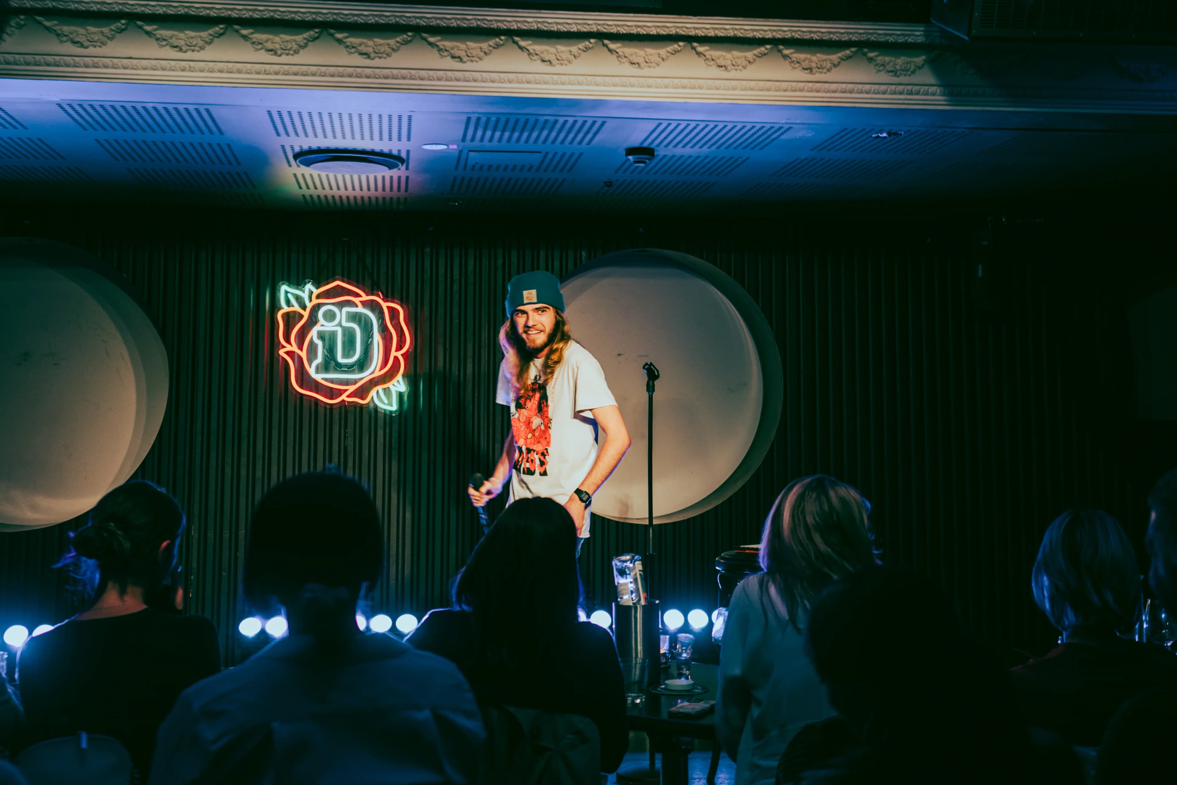 A comedian beside the neon iD rose